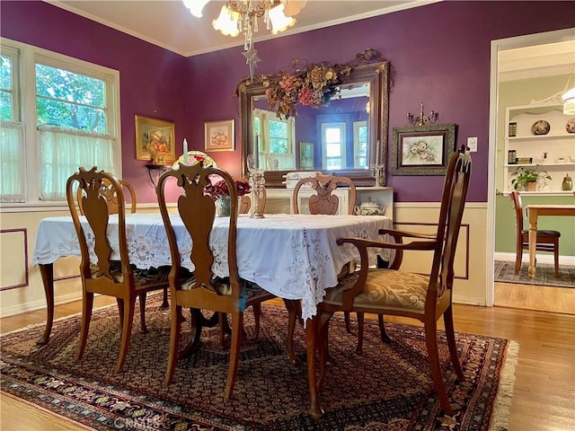 dining room with built in shelves, crown molding, wood-type flooring, and an inviting chandelier