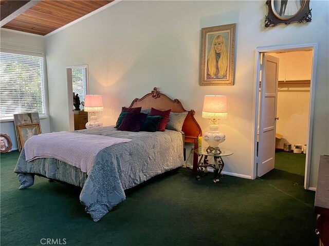 bedroom with a walk in closet, wooden ceiling, ornamental molding, and dark carpet