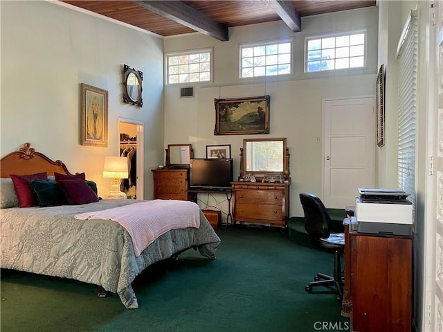 carpeted bedroom with a high ceiling, beamed ceiling, a walk in closet, a closet, and wood ceiling