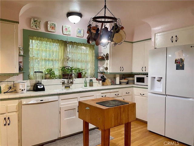 kitchen featuring tile counters, light hardwood / wood-style flooring, pendant lighting, white appliances, and white cabinets