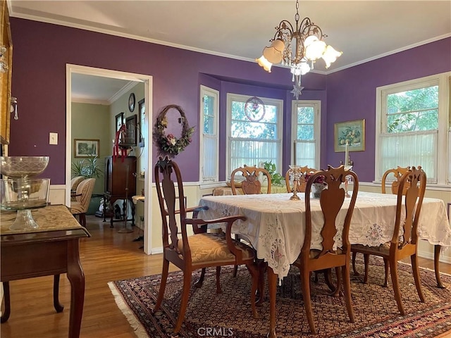 dining area featuring plenty of natural light, an inviting chandelier, hardwood / wood-style floors, and ornamental molding