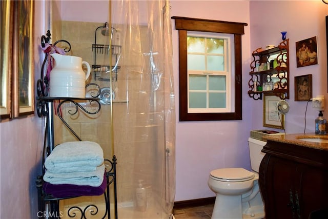 bathroom featuring toilet, a tile shower, and vanity