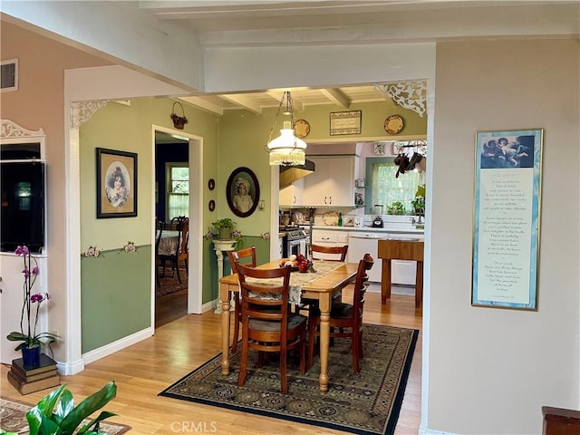 dining room with beamed ceiling and light wood-type flooring