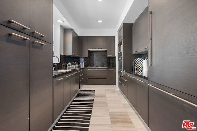 kitchen featuring sink, stainless steel appliances, dark stone countertops, and tasteful backsplash