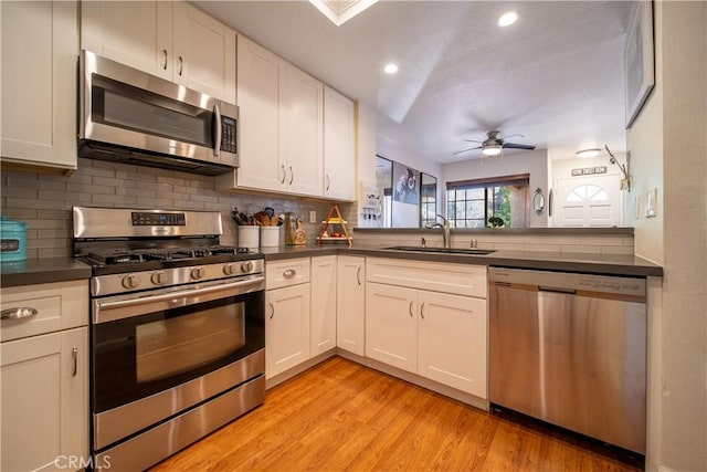 kitchen featuring ceiling fan, sink, stainless steel appliances, light hardwood / wood-style floors, and white cabinets