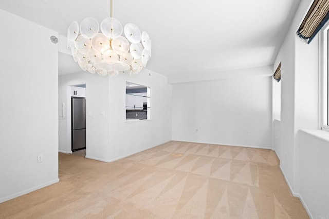 empty room with light colored carpet, an inviting chandelier, and baseboards