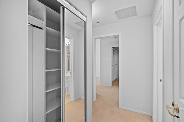 interior space featuring attic access, visible vents, baseboards, and light carpet