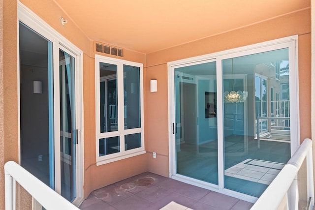 view of exterior entry with a balcony and visible vents