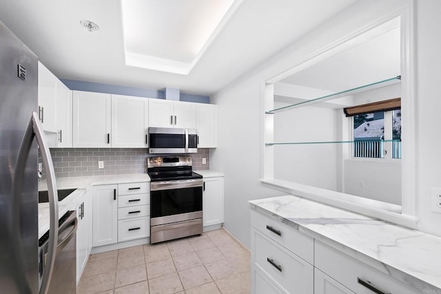 kitchen with stainless steel appliances, light stone countertops, white cabinets, and tasteful backsplash