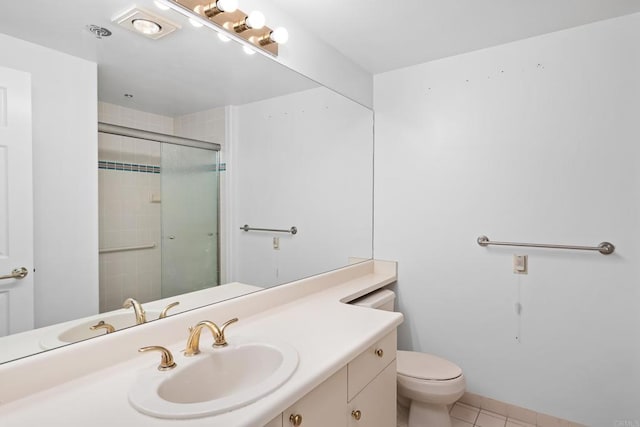 bathroom with vanity, toilet, a tile shower, and tile patterned floors