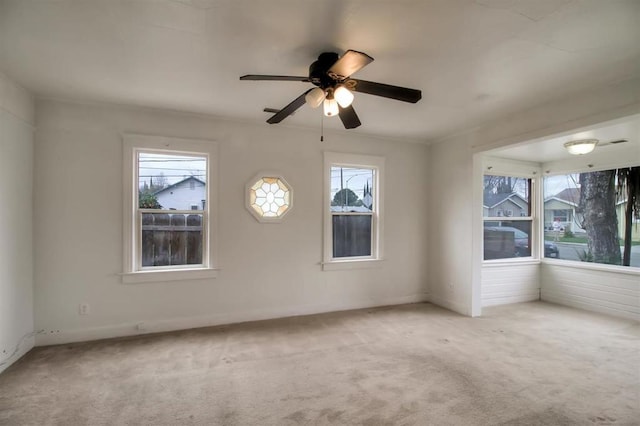 carpeted spare room featuring plenty of natural light and ceiling fan