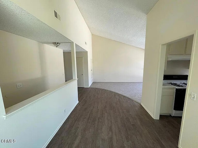 corridor featuring high vaulted ceiling, dark hardwood / wood-style flooring, and a textured ceiling