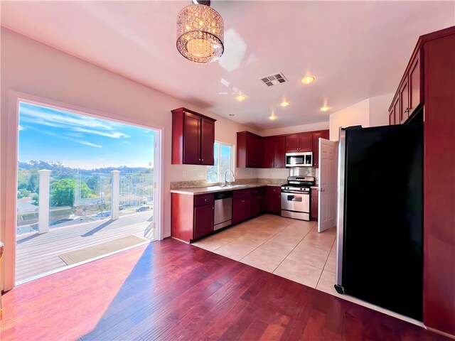 kitchen featuring sink, light hardwood / wood-style floors, decorative light fixtures, and appliances with stainless steel finishes