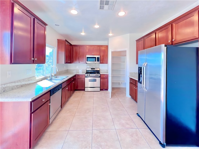 kitchen featuring light tile patterned flooring, light stone countertops, sink, and appliances with stainless steel finishes