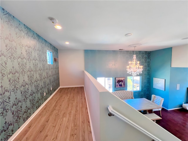 corridor with hardwood / wood-style floors and a chandelier