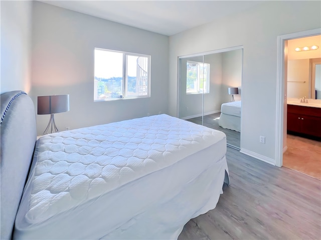 bedroom with connected bathroom, hardwood / wood-style flooring, and a closet