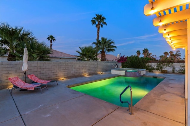 pool at dusk featuring a patio area and an in ground hot tub