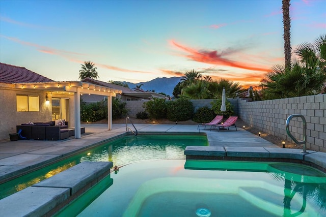 pool at dusk with a mountain view, a patio, and an outdoor hangout area