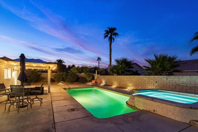 pool at dusk featuring an in ground hot tub and a patio area