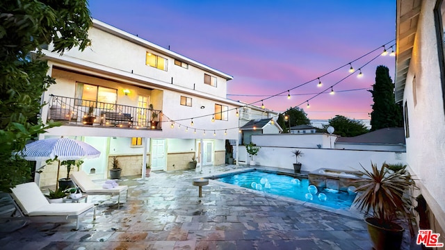 pool at dusk featuring a patio