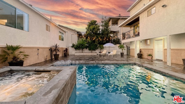 pool at dusk featuring a patio