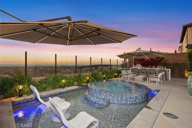 pool at dusk with an in ground hot tub, pool water feature, a patio, and a water slide