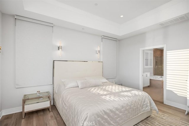 bedroom with hardwood / wood-style flooring and ensuite bath