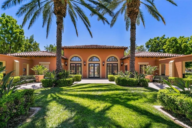 mediterranean / spanish house featuring a front yard and french doors