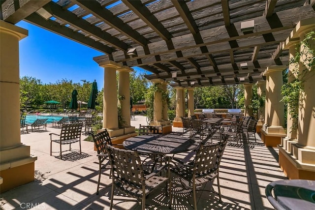 view of patio featuring a pergola, an outdoor kitchen, and a community pool