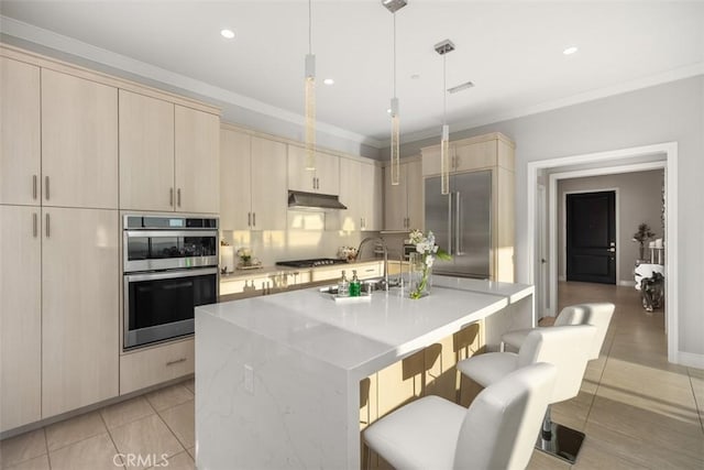 kitchen with a kitchen breakfast bar, a center island with sink, decorative light fixtures, and appliances with stainless steel finishes