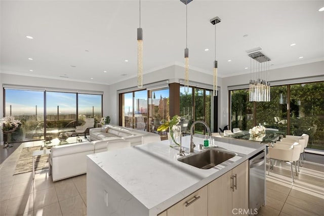 kitchen with light stone countertops, sink, light tile patterned floors, hanging light fixtures, and an island with sink