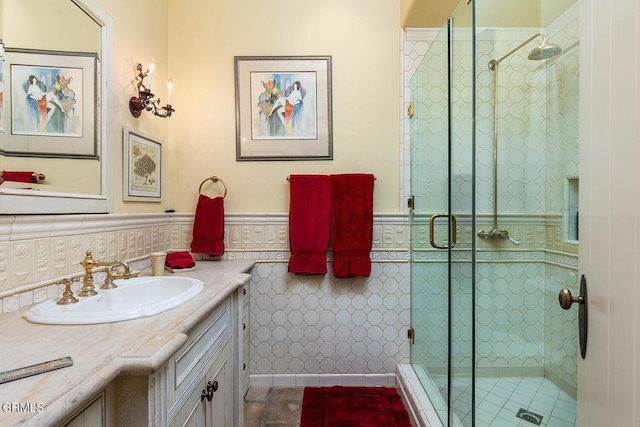 bathroom with tile patterned floors, tile walls, vanity, and an enclosed shower