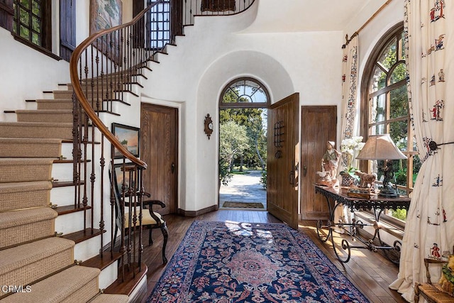 entrance foyer with dark hardwood / wood-style flooring and a towering ceiling