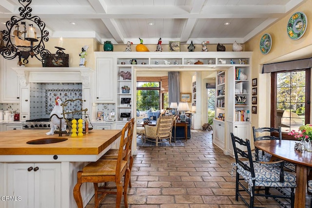 kitchen featuring white cabinets, butcher block countertops, and plenty of natural light