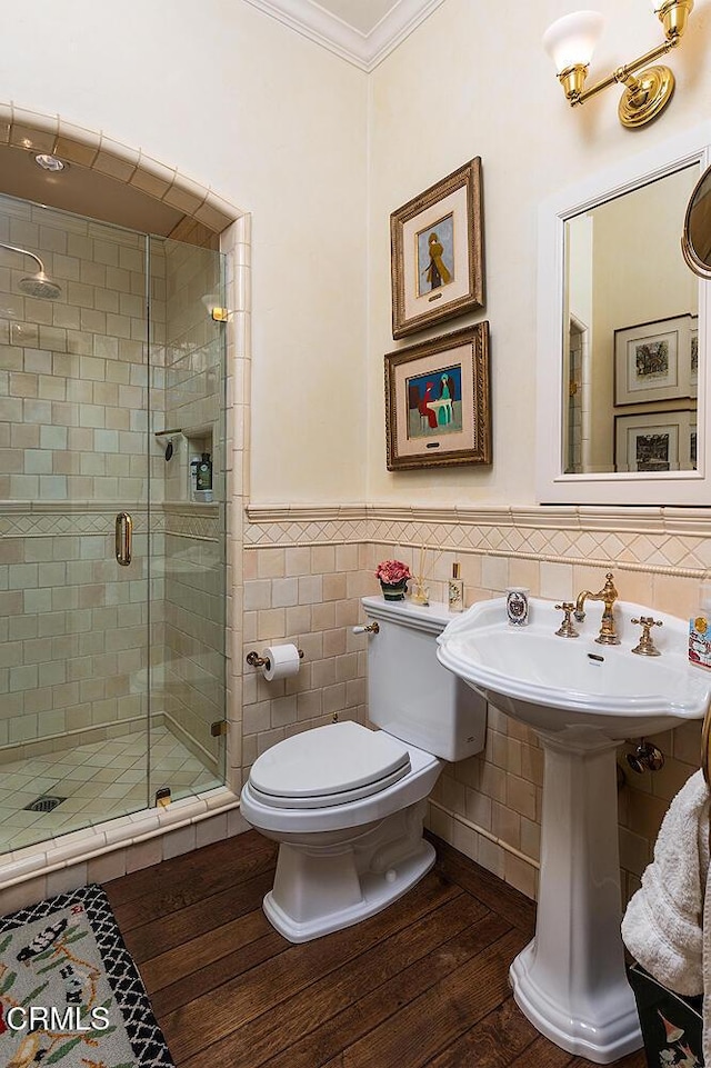 bathroom featuring a shower with shower door, wood-type flooring, tile walls, and ornamental molding