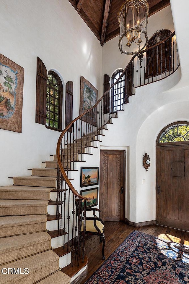 foyer entrance with an inviting chandelier, beamed ceiling, high vaulted ceiling, hardwood / wood-style floors, and wood ceiling