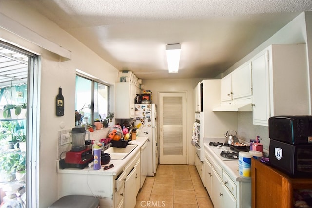 kitchen featuring a textured ceiling, light tile patterned floors, white appliances, and white cabinetry