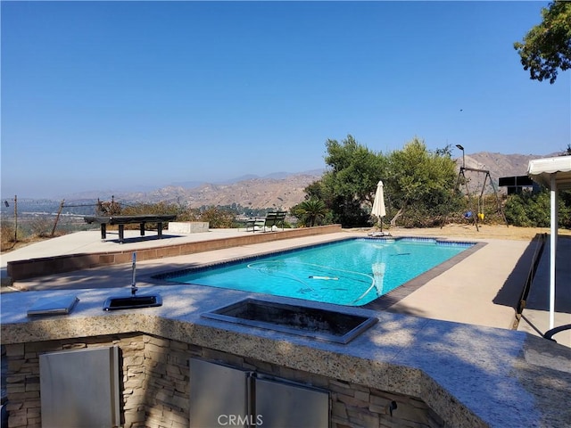 view of pool with a mountain view and a patio