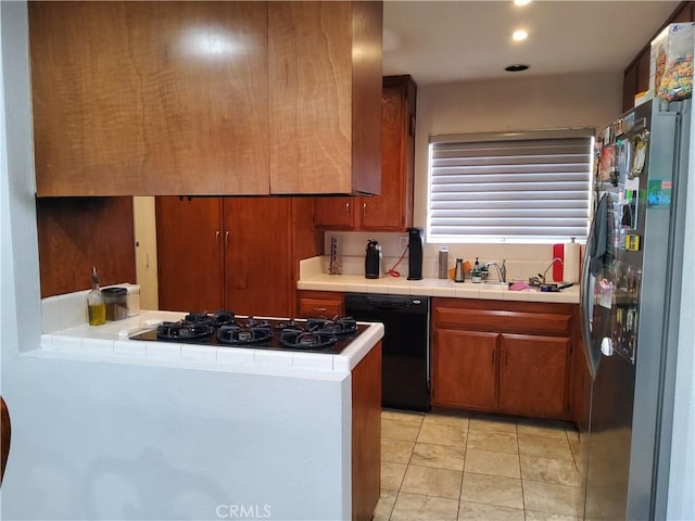 kitchen featuring stainless steel refrigerator, sink, dishwasher, gas stovetop, and light tile patterned floors