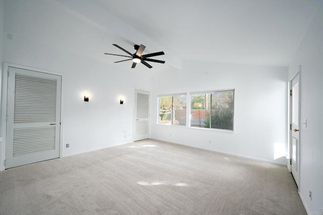 carpeted spare room featuring lofted ceiling with beams and ceiling fan