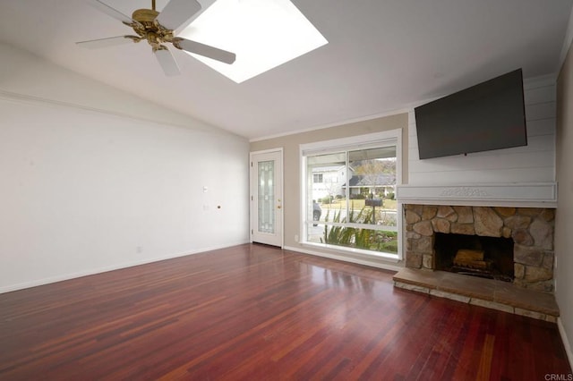 unfurnished living room featuring dark hardwood / wood-style flooring, a stone fireplace, lofted ceiling with skylight, and ceiling fan