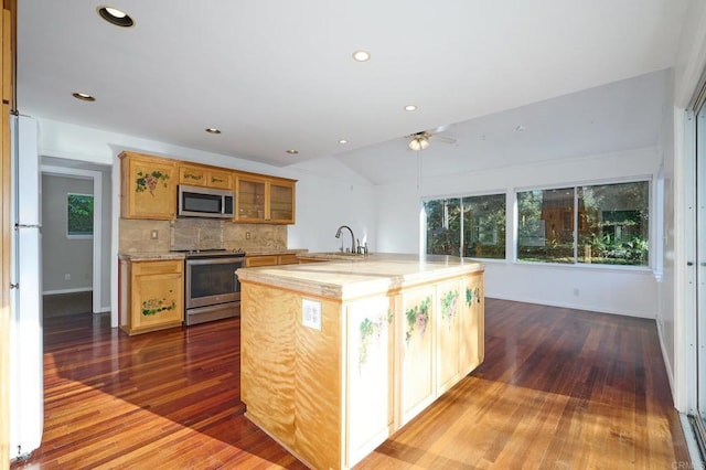 kitchen with dark wood-type flooring, sink, tasteful backsplash, vaulted ceiling, and appliances with stainless steel finishes