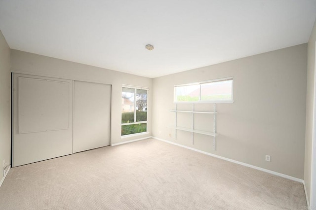 unfurnished bedroom featuring light colored carpet and a closet