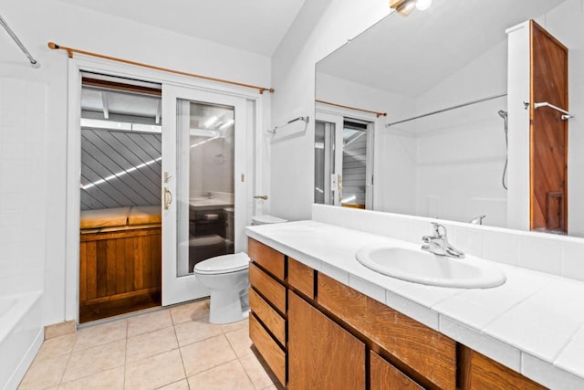 bathroom featuring vanity, tile patterned flooring, vaulted ceiling, and toilet