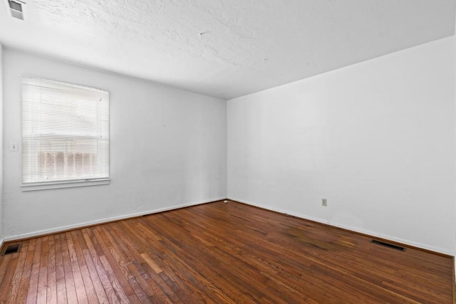 unfurnished room with hardwood / wood-style flooring and a textured ceiling