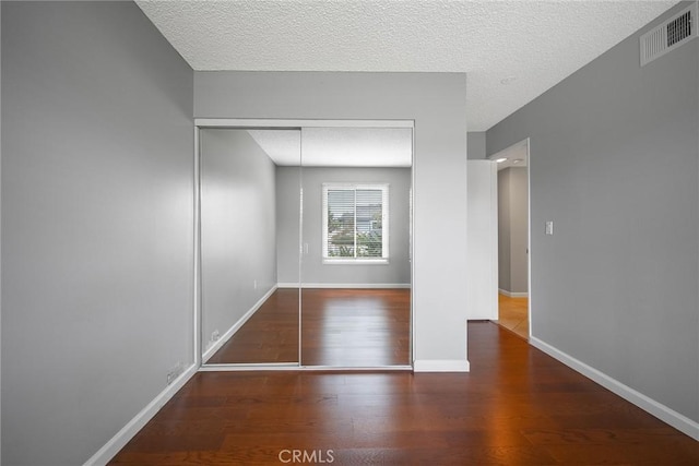 spare room with a textured ceiling and hardwood / wood-style flooring