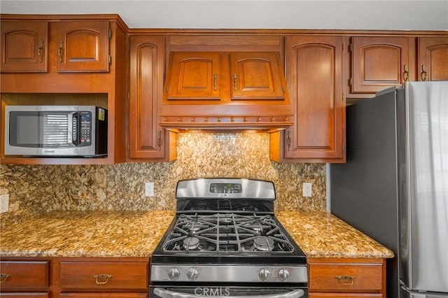 kitchen featuring backsplash, light stone countertops, custom exhaust hood, and appliances with stainless steel finishes