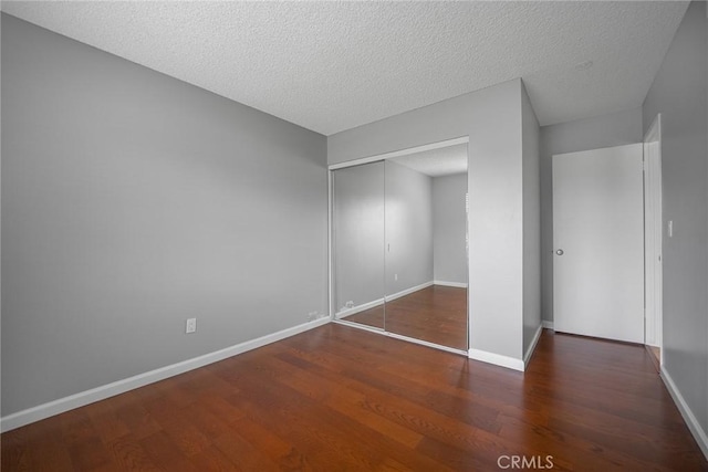 unfurnished bedroom featuring a textured ceiling, a closet, and dark hardwood / wood-style floors