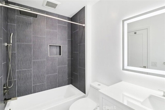 full bathroom featuring toilet, vanity, and tiled shower / bath