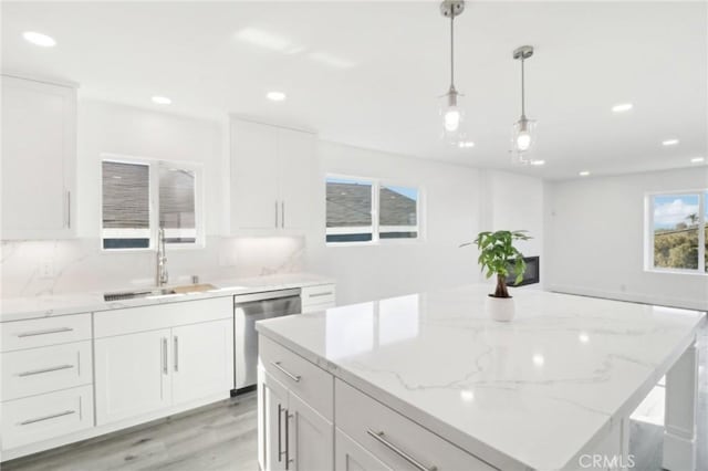 kitchen featuring decorative light fixtures, sink, white cabinetry, and stainless steel dishwasher